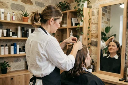 Coiffeuse professionnelle en Vendée coupant les cheveux d'une cliente dans un salon moderne au décor en pierre apparente